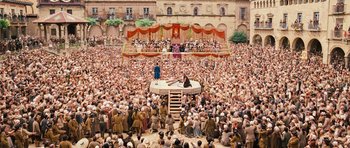 Movie still from “Perfume: The Story of a Murderer” (2006), directed by Tom Tykwer – A crowd of people sitting and standing around a stage; Extreme Wide shot, High angle