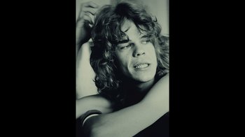 Movie still from “Personality Crisis: One Night Only” (2022), directed by David Tedeschi – A man with long hair is posing for a picture; Close Up shot, Low angle