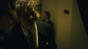 Movie still from “Personality Crisis: One Night Only” (2022), directed by David Tedeschi – A man in a suit and tie standing in a room; Close Up shot, Low angle