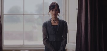 Movie still from “Persuasion” (2022), directed by Carrie Cracknell – A woman standing in front of a large window; Medium shot, Over the shoulder angle