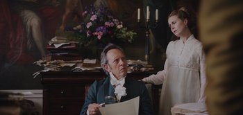 Movie still from “Persuasion” (2022), directed by Carrie Cracknell – An old man sitting in front of a young girl; Medium shot, Over the shoulder angle