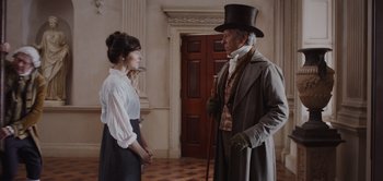 Movie still from “Persuasion” (2022), directed by Carrie Cracknell – A man and a woman standing next to each other in a room; Medium shot, Over the shoulder angle