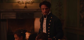 Movie still from “Persuasion” (2022), directed by Carrie Cracknell – A man wearing a black jacket and a white shirt; Medium shot, Over the shoulder angle