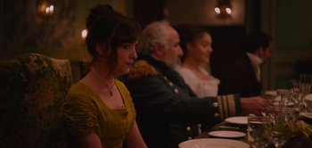 Movie still from “Persuasion” (2022), directed by Carrie Cracknell – Three people are sitting at a table in a restaurant; Medium shot, Over the shoulder angle