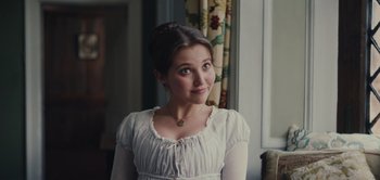 Movie still from “Persuasion” (2022), directed by Carrie Cracknell – A woman in a white dress looking at the camera; Close Up shot, Over the shoulder angle