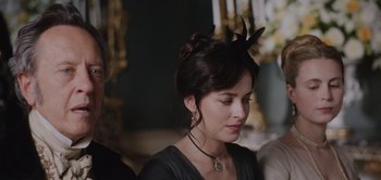 Movie still from “Persuasion” (2022), directed by Carrie Cracknell – A woman wearing a black dress and a black headband; Close Up shot, Over the shoulder angle