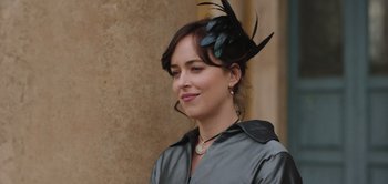 Movie still from “Persuasion” (2022), directed by Carrie Cracknell – A woman wearing a black hat with feathers on it; Close Up shot, Over the shoulder angle