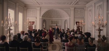 Movie still from “Persuasion” (2022), directed by Carrie Cracknell – A group of people sitting in a room with chairs; Extreme Wide shot, High angle