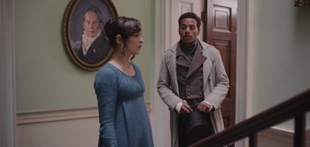 Movie still from “Persuasion” (2022), directed by Carrie Cracknell – A man and a woman standing next to each other in a room; Medium shot, Over the shoulder angle