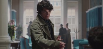 Movie still from “Persuasion” (2022), directed by Carrie Cracknell – A young man holding a cigarette in his hand; Close Up shot, Over the shoulder angle