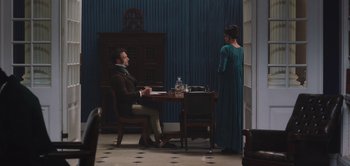 Movie still from “Persuasion” (2022), directed by Carrie Cracknell – A man sitting at a table in front of a woman; Wide shot, Over the shoulder angle