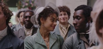 Movie still from “Persuasion” (2022), directed by Carrie Cracknell – A group of people that are standing around a woman; Close Up shot, Over the shoulder angle