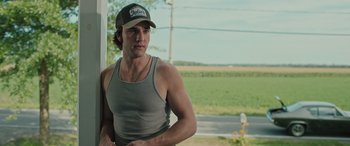 Movie still from “Pet Sematary: Bloodlines” (2023), directed by Lindsey Anderson Beer – A man wearing a baseball cap and a tank top; Medium shot, Over the shoulder angle