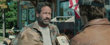 Movie still from “Pet Sematary: Bloodlines” (2023), directed by Lindsey Anderson Beer – A man holding a bag of food while standing in front of a store; Close Up shot, Over the shoulder angle