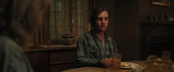 Movie still from “Pet Sematary: Bloodlines” (2023), directed by Lindsey Anderson Beer – A man sitting at a table with a drink in front of him; Medium shot, Over the shoulder angle