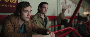Movie still from “Pet Sematary: Bloodlines” (2023), directed by Lindsey Anderson Beer – Two men are sitting in a row of red benches; Close Up shot, Over the shoulder angle