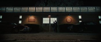 Movie still from “Pet Sematary: Bloodlines” (2023), directed by Lindsey Anderson Beer – Two people standing in front of a building at night; Extreme Wide shot, Low angle