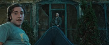 Movie still from “Pet Sematary: Bloodlines” (2023), directed by Lindsey Anderson Beer – A man standing in front of an open door; Wide shot, Low angle