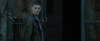 Movie still from “Pet Sematary: Bloodlines” (2023), directed by Lindsey Anderson Beer – A young man standing in front of a door; Medium shot, Over the shoulder angle
