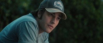 Movie still from “Pet Sematary: Bloodlines” (2023), directed by Lindsey Anderson Beer – A young man wearing a baseball cap and a gray shirt; Close Up shot, Low angle