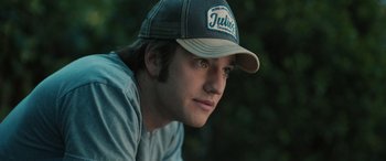 Movie still from “Pet Sematary: Bloodlines” (2023), directed by Lindsey Anderson Beer – A young man wearing a baseball cap and a t - shirt; Close Up shot, Low angle