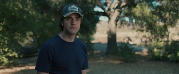 Movie still from “Pet Sematary: Bloodlines” (2023), directed by Lindsey Anderson Beer – A young man wearing a hat standing next to a tree; Close Up shot, Over the shoulder angle