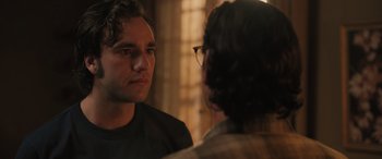 Movie still from “Pet Sematary: Bloodlines” (2023), directed by Lindsey Anderson Beer – A man looking into a mirror while standing next to another man; Close Up shot, Over the shoulder angle