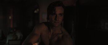 Movie still from “Pet Sematary: Bloodlines” (2023), directed by Lindsey Anderson Beer – A shirtless man with headphones in a dark room; Close Up shot, Over the shoulder angle