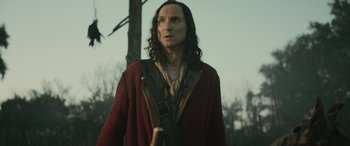 Movie still from “Pet Sematary: Bloodlines” (2023), directed by Lindsey Anderson Beer – A man with long black hair wearing a red coat; Medium shot, Low angle