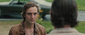 Movie still from “Pet Sematary: Bloodlines” (2023), directed by Lindsey Anderson Beer – A young man wearing a leather jacket and ear phones; Close Up shot, Over the shoulder angle