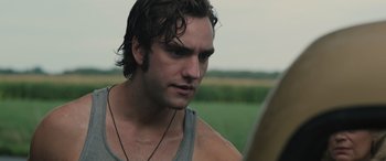 Movie still from “Pet Sematary: Bloodlines” (2023), directed by Lindsey Anderson Beer – A person wearing a tank top near a field; Close Up shot, Over the shoulder angle