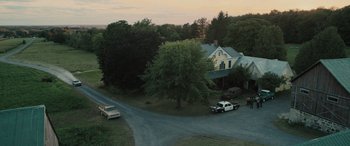Movie still from “Pet Sematary: Bloodlines” (2023), directed by Lindsey Anderson Beer – An aerial view of a house and a car parked on the side of the road; Extreme Wide shot, High angle