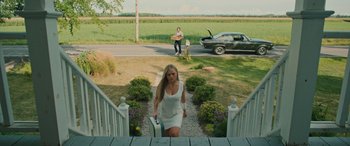 Movie still from “Pet Sematary: Bloodlines” (2023), directed by Lindsey Anderson Beer – A woman walking up a set of stairs holding a suitcase; Wide shot, High angle