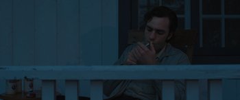 Movie still from “Pet Sematary: Bloodlines” (2023), directed by Lindsey Anderson Beer – A young man smoking a cigarette in front of a window; Medium shot, Low angle