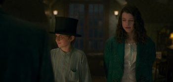 Movie still from “Peter Pan & Wendy” (2023), directed by David Lowery – A boy wearing a top hat standing next to a girl; Medium shot, Over the shoulder angle
