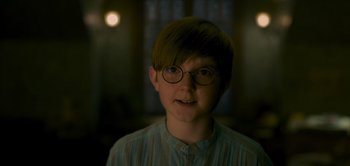 Movie still from “Peter Pan & Wendy” (2023), directed by David Lowery – A young man wearing glasses and a striped shirt; Close Up shot, Over the shoulder angle