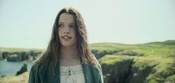 Movie still from “Peter Pan & Wendy” (2023), directed by David Lowery – A young woman with long hair wearing a green sweater; Close Up shot, Low angle