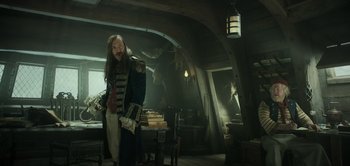 Movie still from “Peter Pan & Wendy” (2023), directed by David Lowery – A man standing in a room full of books; Medium shot, Over the shoulder angle