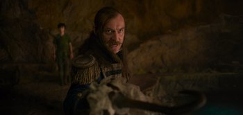 Movie still from “Peter Pan & Wendy” (2023), directed by David Lowery – A man with long hair and a beard wearing a brown jacket; Medium shot, Over the shoulder angle