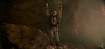Movie still from “Peter Pan & Wendy” (2023), directed by David Lowery – An old man dressed as a pirate is holding a knife and looking up; Medium shot, Low angle