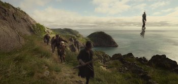Movie still from “Peter Pan & Wendy” (2023), directed by David Lowery – A group of people walking up a hill near the ocean; Extreme Wide shot, High angle