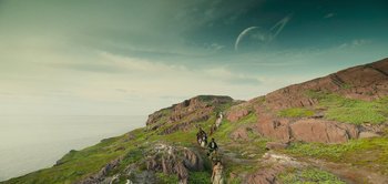 Movie still from “Peter Pan & Wendy” (2023), directed by David Lowery – A group of people walking up a hill on horseback; Extreme Wide shot, High angle