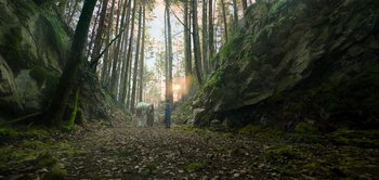 Movie still from “Peter Pan & Wendy” (2023), directed by David Lowery – Two people are walking through the woods with a horse; Extreme Wide shot, Low angle