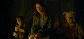 Movie still from “Peter Pan & Wendy” (2023), directed by David Lowery – A woman sitting in front of a fireplace; Medium shot, High angle