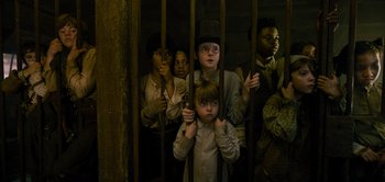 Movie still from “Peter Pan & Wendy” (2023), directed by David Lowery – A group of people standing in a jail cell; Medium shot, High angle