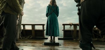 Movie still from “Peter Pan & Wendy” (2023), directed by David Lowery – A woman standing on a wooden deck looking out at the ocean; Wide shot, Over the shoulder angle