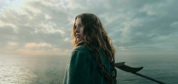 Movie still from “Peter Pan & Wendy” (2023), directed by David Lowery – A woman standing on top of a beach next to the ocean; Medium shot, Low angle