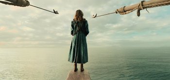 Movie still from “Peter Pan & Wendy” (2023), directed by David Lowery – A woman standing on a pier looking out at the ocean; Wide shot, Low angle