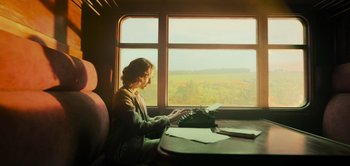 Movie still from “Peter Pan & Wendy” (2023), directed by David Lowery – A woman sitting at a table typing on a typewriter; Medium shot, Low angle