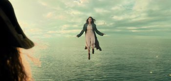 Movie still from “Peter Pan & Wendy” (2023), directed by David Lowery – A woman is jumping in the air over a body of water; Wide shot, Low angle